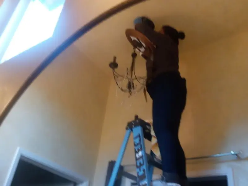 Electrician installing a chandelier in a Fairview residence